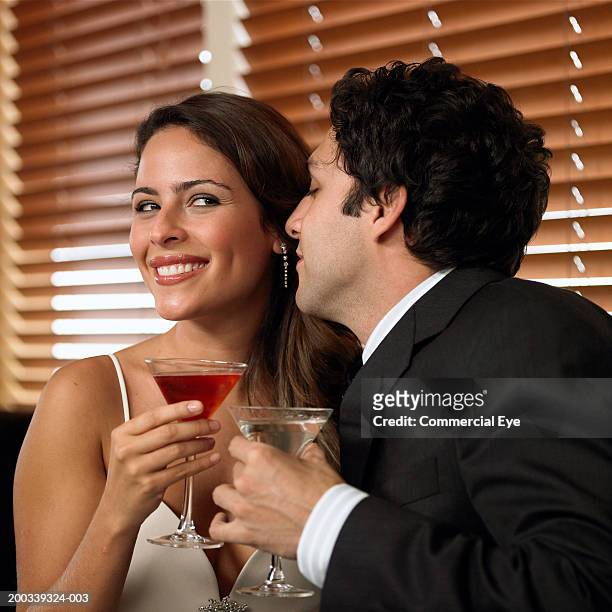couple holding drinks at bar, man leaning towards woman, side view - woman whisper to man stock pictures, royalty-free photos & images