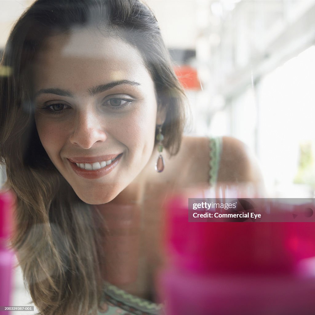 Woman looking through store window display, close-up