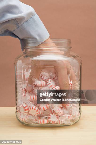 man grabing handful of peppermint candies in jar - candy jar stock pictures, royalty-free photos & images