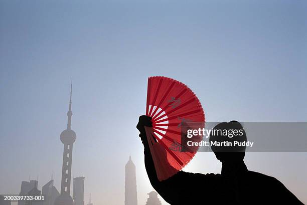 china, shanghai, woman practicing t'ai chi, holding fan, sunrise - chinese fan stock pictures, royalty-free photos & images