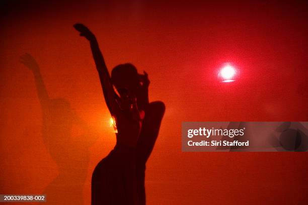 young woman with one hand raised, shadow on red background - bauchtänzerin stock-fotos und bilder