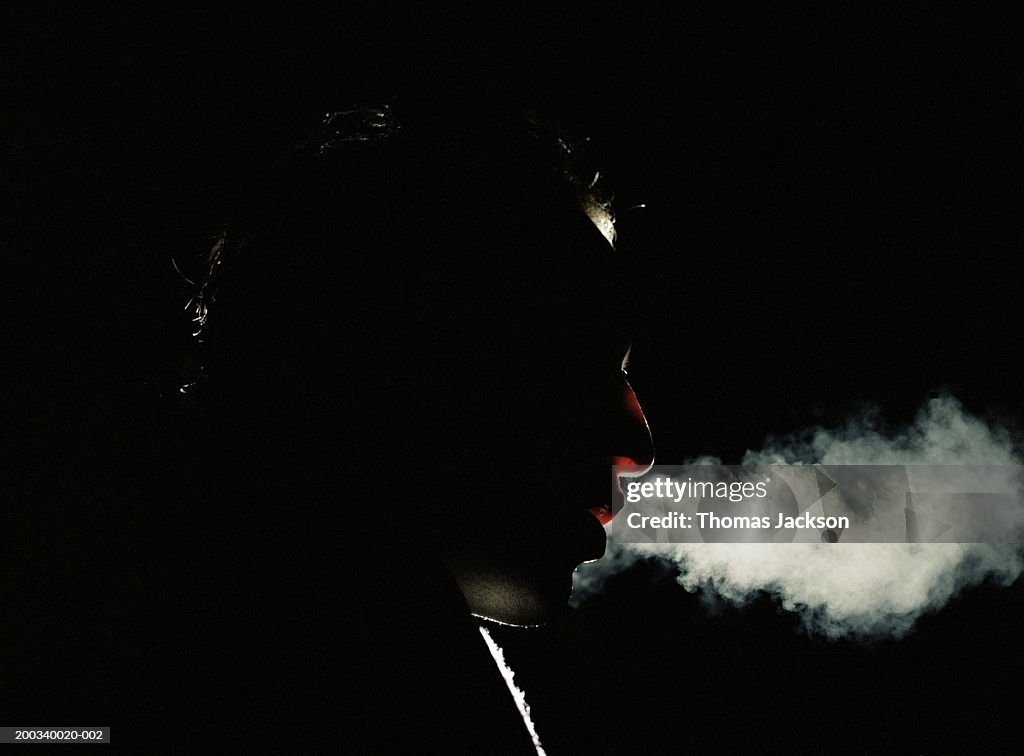 Man exhaling vapor, side view, close-up, night