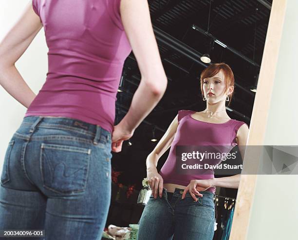 young woman trying on jeans in front of mirror, low angle view - 超小號 個照片及圖片檔