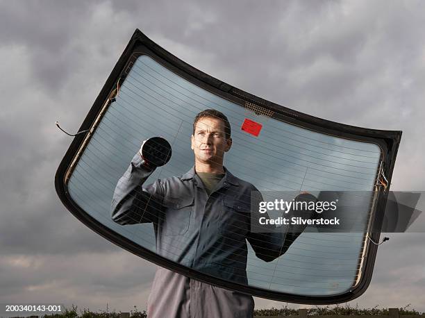 car mechanic holding rear windscreen with suction pads - windshield foto e immagini stock