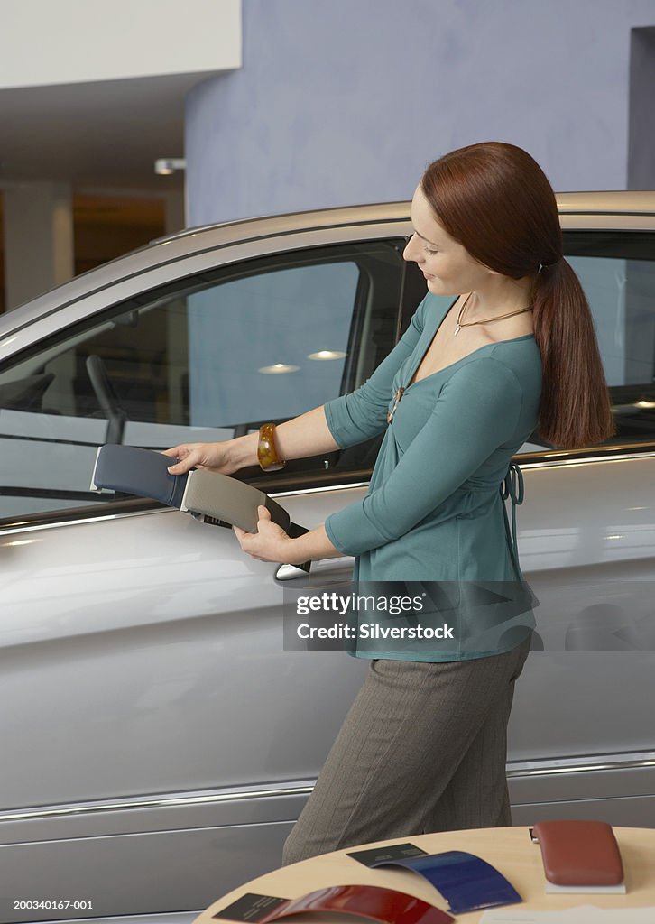 Woman looking at colour samples against car in showroom