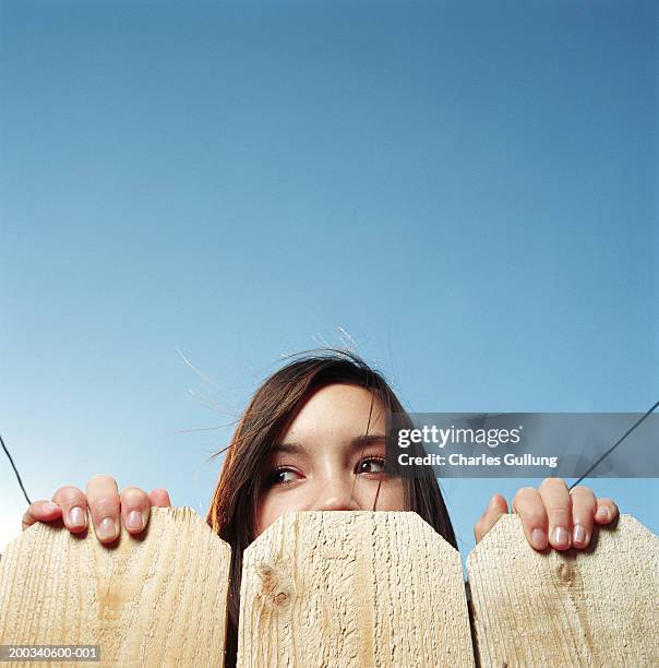 teenage girl (14-16) looking over fence, low angle view, high section - peek fotografías e imágenes de stock