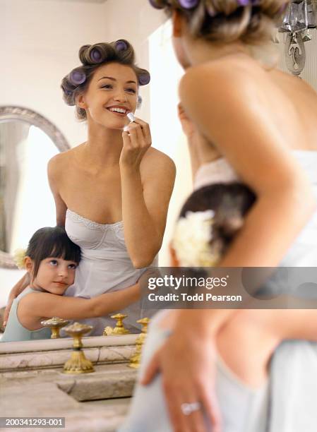 flower girl (3-5) hugging bride as she applies lipstick in mirror - woman lipstick rearview stock pictures, royalty-free photos & images