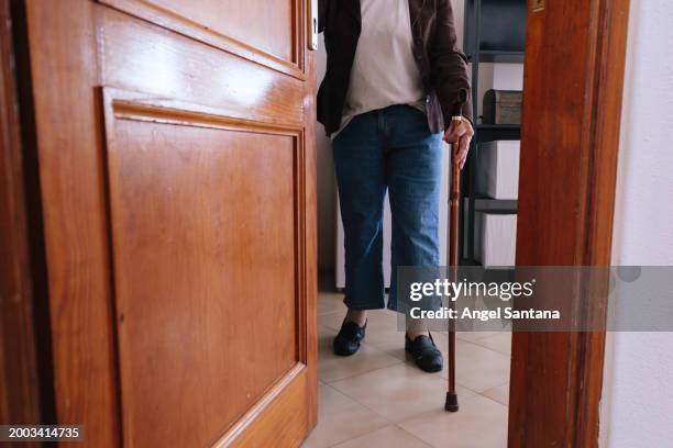 senior person with cane entering wooden doorway - walking cane stock pictures, royalty-free photos & images