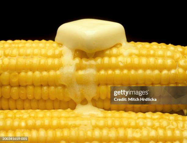 butter melting on ear of corn, close-up - corn on black stockfoto's en -beelden