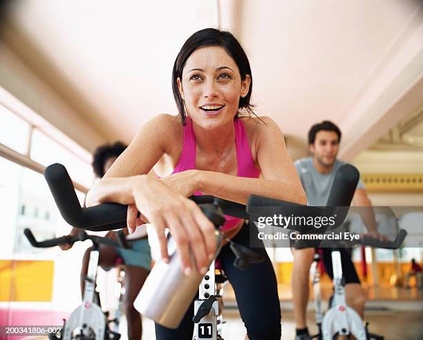 three people sitting on exercising bikes in gym, close-up - exercise bike fotografías e imágenes de stock