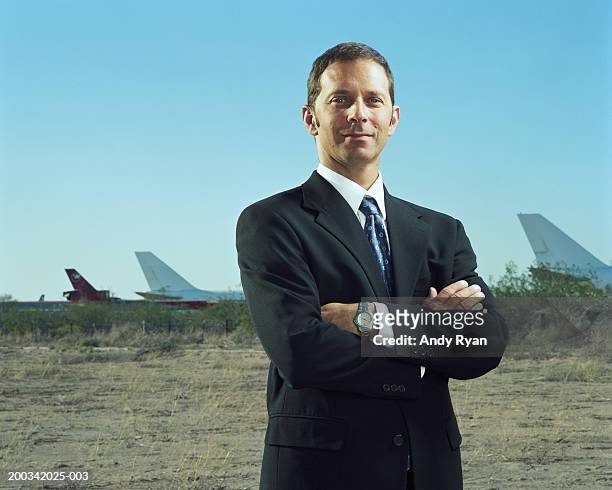 man in suit, standing on field, airplanes in background, portrait - portrait man suit smiling light background stock pictures, royalty-free photos & images