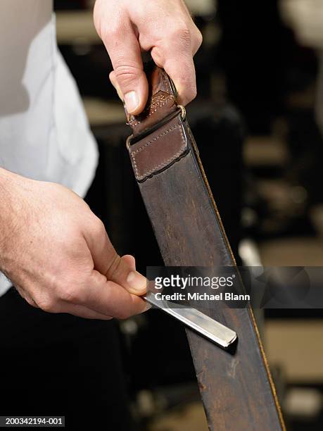 barber sharpening razor blade on leather strip, close-up of hands - straight razor stock pictures, royalty-free photos & images