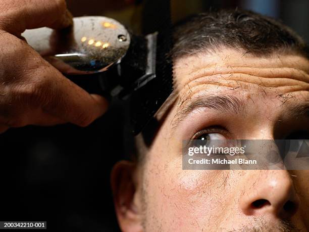 barber shaving man's hair with electric razor, close-up - head shave stockfoto's en -beelden