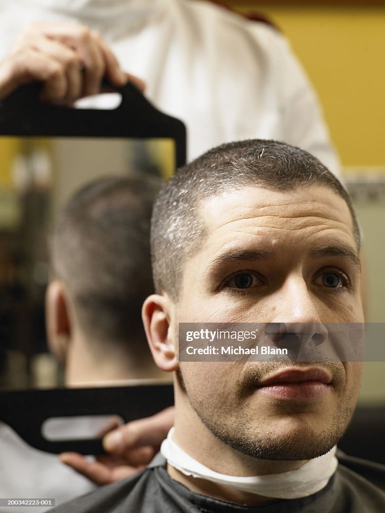 Barber holding mirror behind man's head, close-up of man