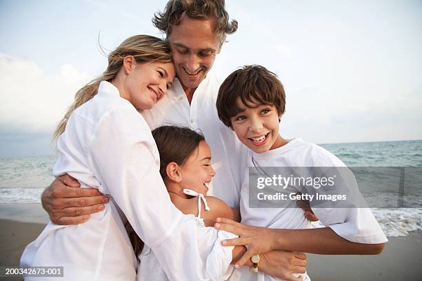 family on beach, embracing, smiling, children (7-9) - barcelona beach stock pictures, royalty-free photos & images