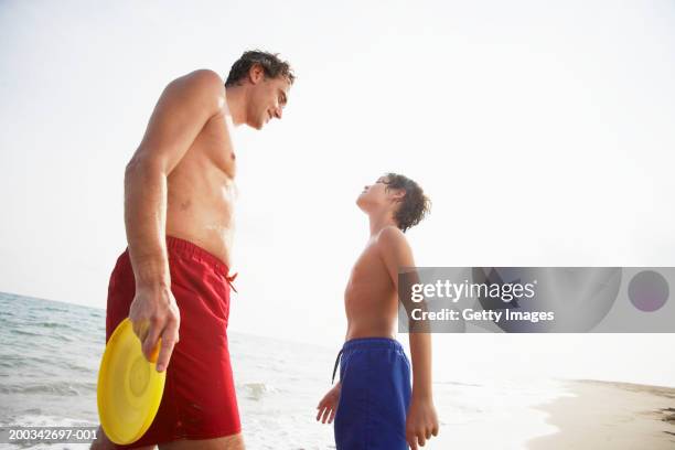 pai segurando o filho disco de plástico de frente para a praia (8-10 anos - calções azuis - fotografias e filmes do acervo