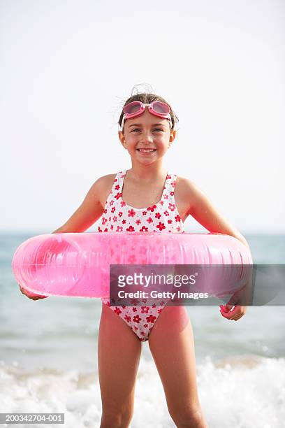 girl (6-8) wearing rubber ring on beach, smiling, portrait - maillot vert stock pictures, royalty-free photos & images