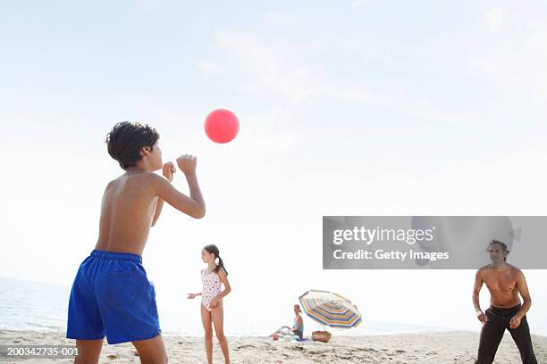 father playing volleyball on beach with son and daughter (7-9) - girls beach volleyball stock pictures, royalty-free photos & images