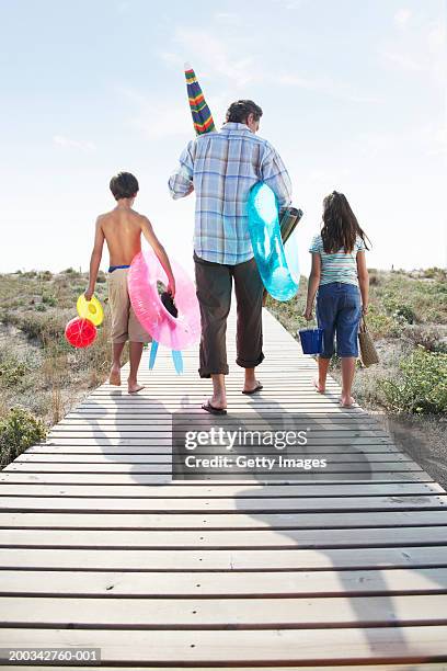 father and children (7-9) on path carrying beach toys, rear view - barcelona free stockfoto's en -beelden