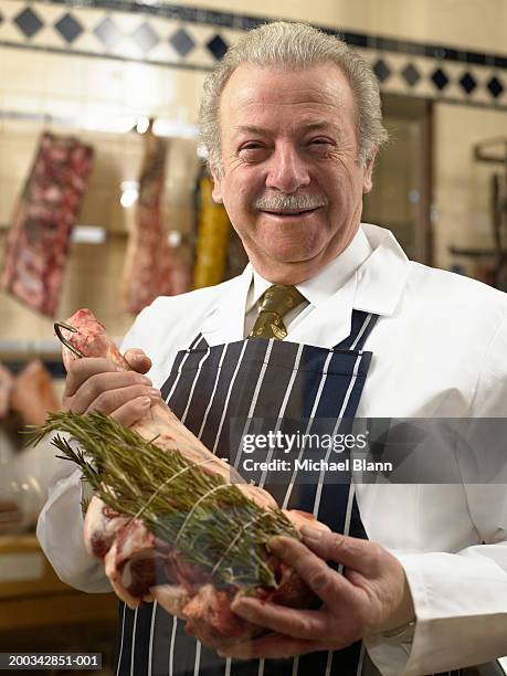 senior male butcher selecting leg of lamb, smiling, portrait - fleischer stock-fotos und bilder