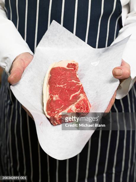 senior male butcher holding sirloin of steak, mid section - butchery stock-fotos und bilder