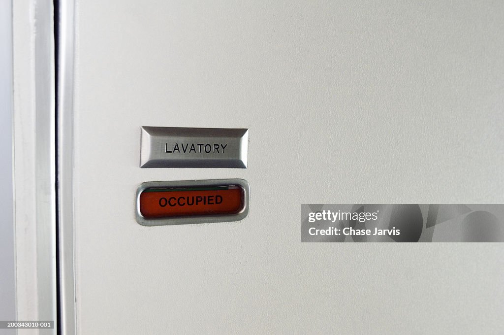 Close-up of airline lavatory door with sign reading 'occupied'