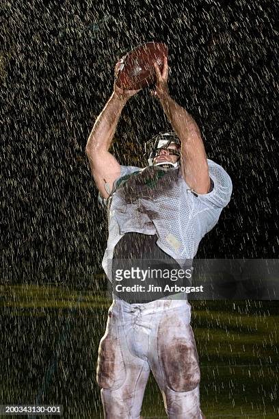 male football player catching football in rain, night - caught in rain stock pictures, royalty-free photos & images