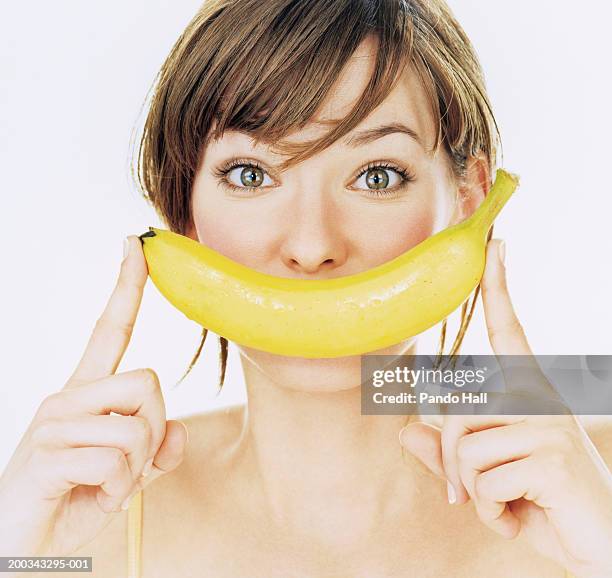 young woman holding banana over mouth, portrait, close-up - banana woman stock pictures, royalty-free photos & images