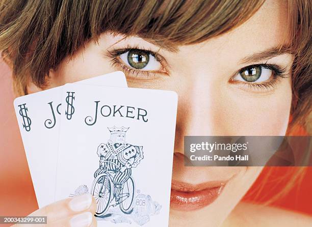 young woman holding up joker playing card, smiling, portrait, close-up - coringa - fotografias e filmes do acervo