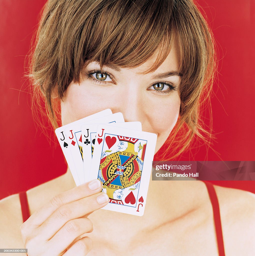 Young woman holding playing cards up to face, portrait, close-up