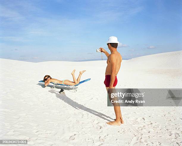 man taking picture of woman lying on sun lounger - see through swimsuit ストックフォトと画像