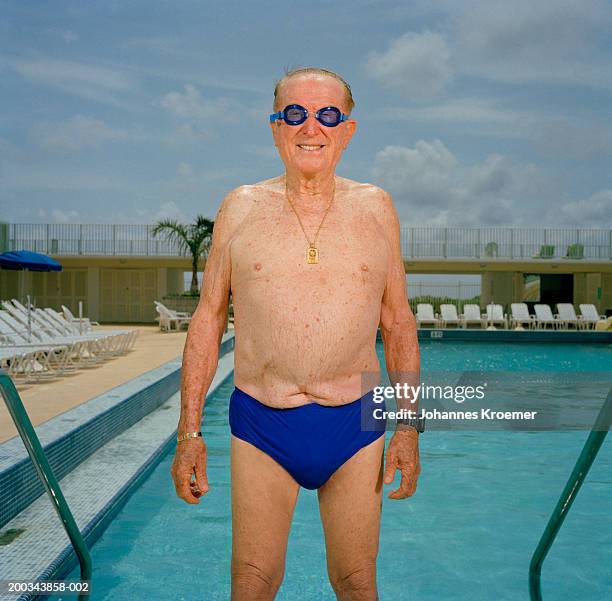 senior man at edge of pool wearing swim goggles, portrait - chest torso stockfoto's en -beelden
