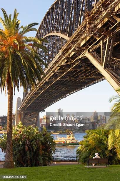 australia, sydney, boat's man on bench beneath harbour bridge - puente del puerto de sidney fotografías e imágenes de stock
