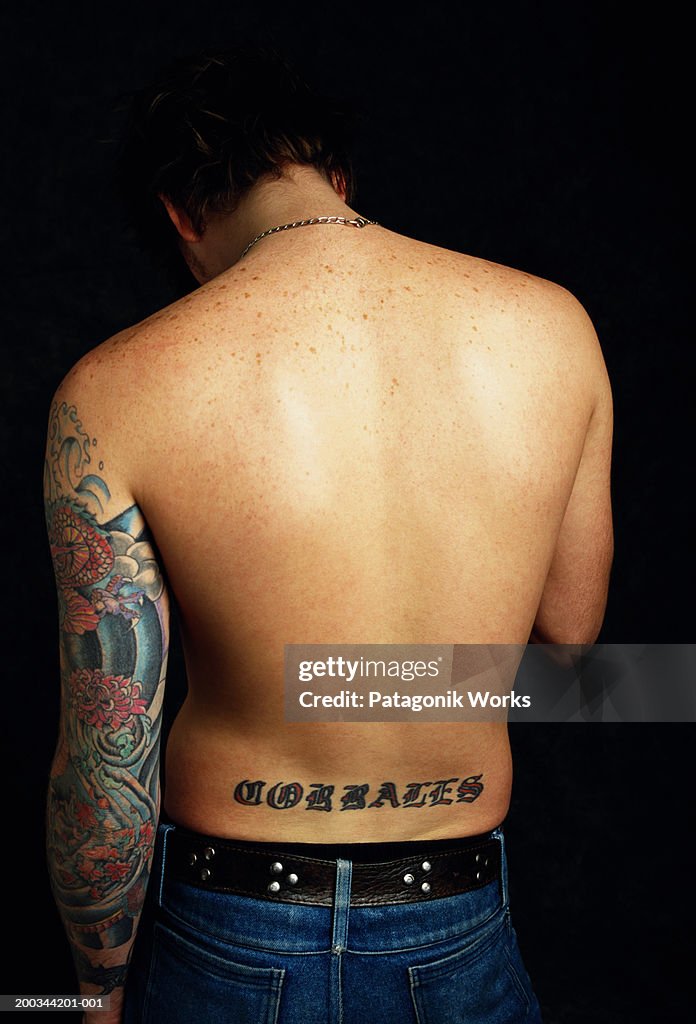 Man with tattoos on arm and back, rear view