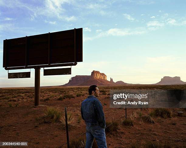 man standing next to silhouette of billboard in desert, side view - us blank billboard stockfoto's en -beelden
