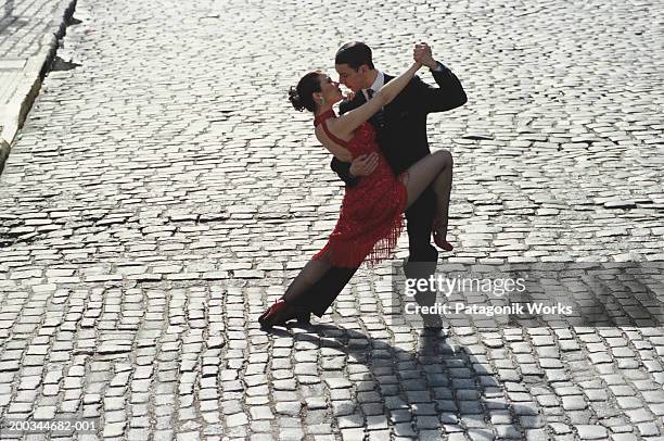 man and woman dancing tango on cobblestone road, elevated view - tango dancers foto e immagini stock
