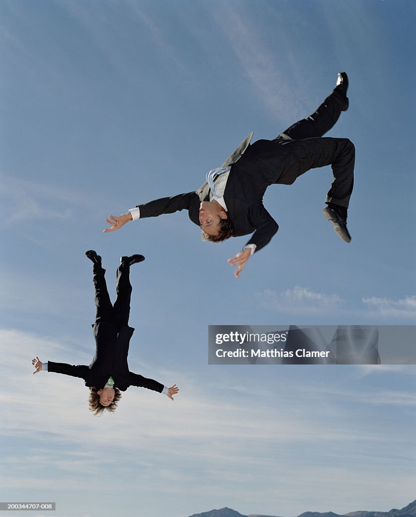 Two businessmen upside down in mid-air