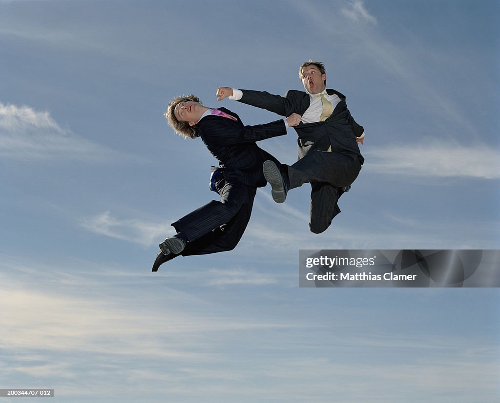 Two businessmen fist fighting in mid air (blurred motion)