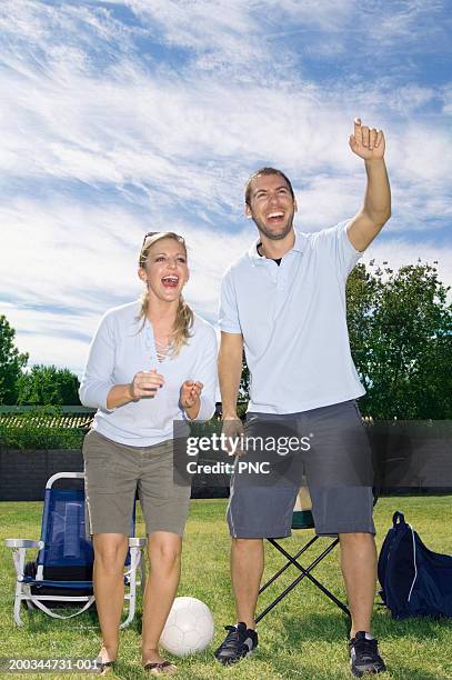 young man and woman cheering on sidelines of soccer game - spielfeldgrenze stock-fotos und bilder