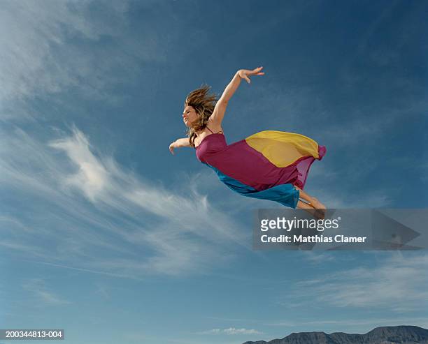 woman flying through sky, side view - volare foto e immagini stock