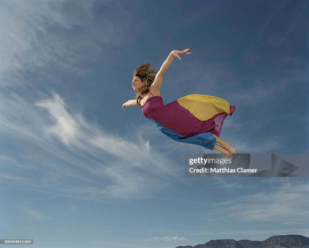Woman flying through sky, side view