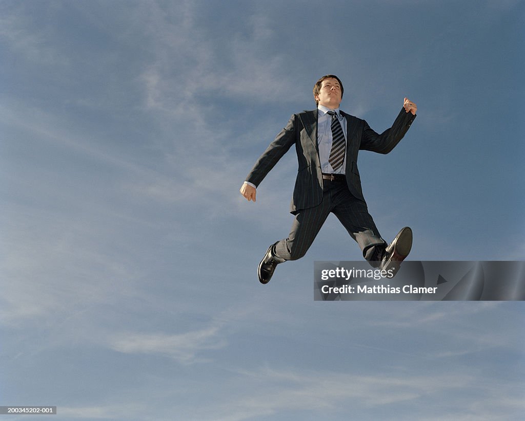 Young businessman walking in mid air, low angle view