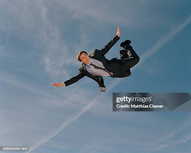 young businessman soaring through sky, portrait, low angle view - horizontal falls stock pictures, royalty-free photos & images