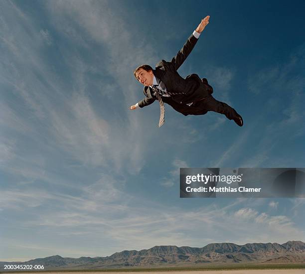 young businessman flying through sky, smiling, side view - 思い切って飛び込む ストックフォトと画像
