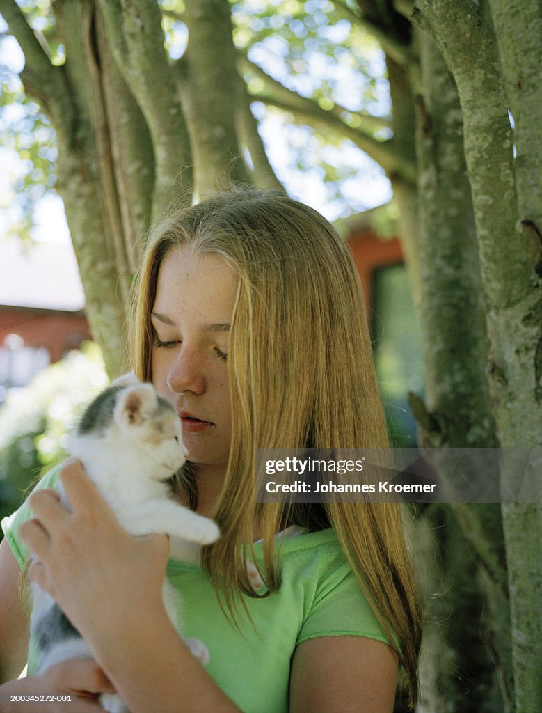 Girl (10-12) holding kitten, close-up