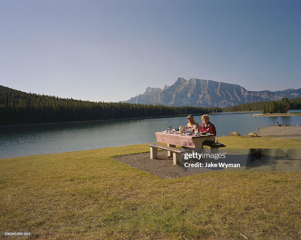 Senior couple having picnic near lake, portrait