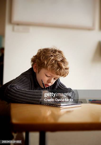 boy (6-9) writing in notebook (focus on face) - kinder schreiben stock-fotos und bilder