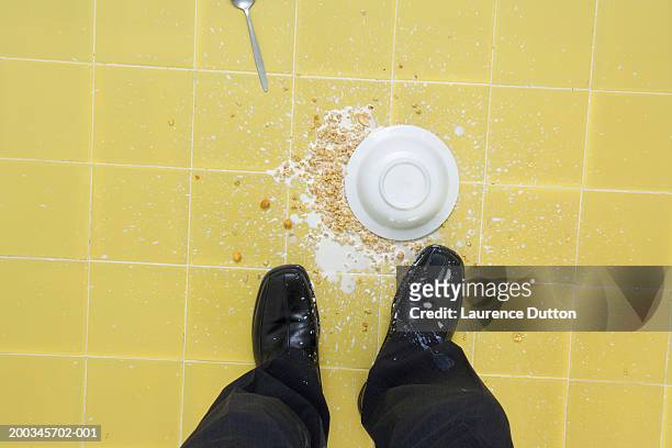 man standing by spilt bowl of milk and cereal, overhead view - scarpa gialla foto e immagini stock