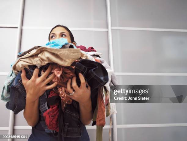 young woman holding pile of laundry, low angle view - washing stock-fotos und bilder