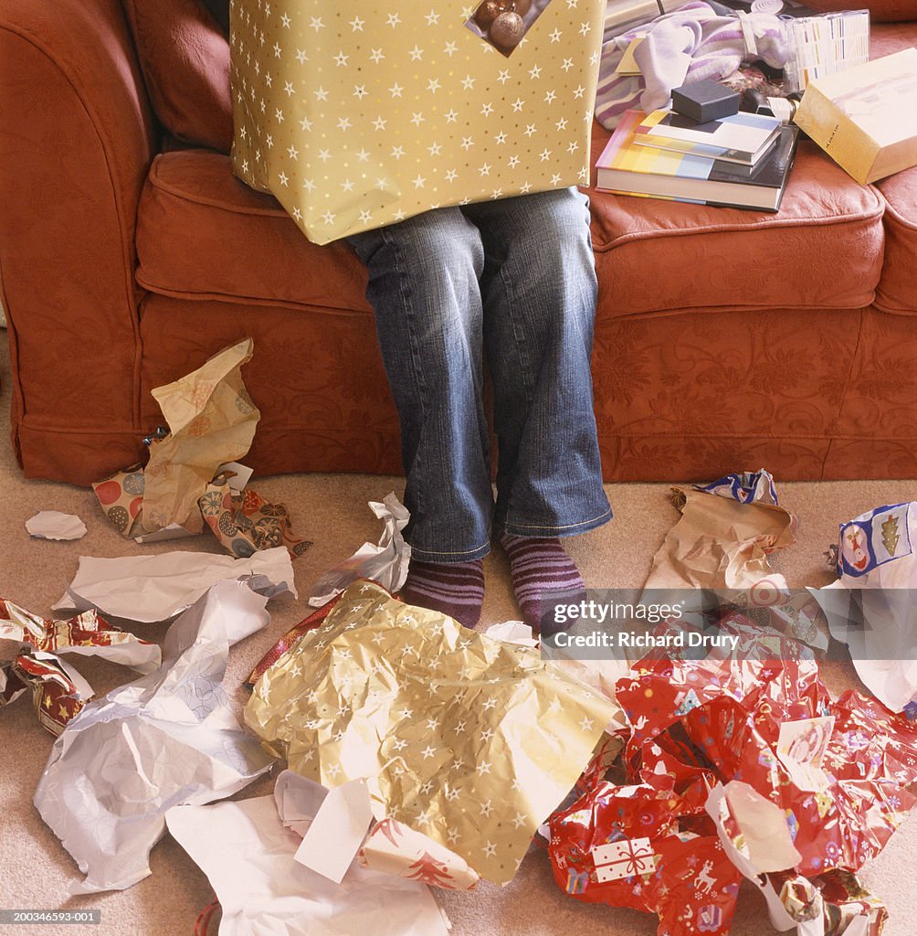 Woman opening presents, wrapping paper on floor, low section